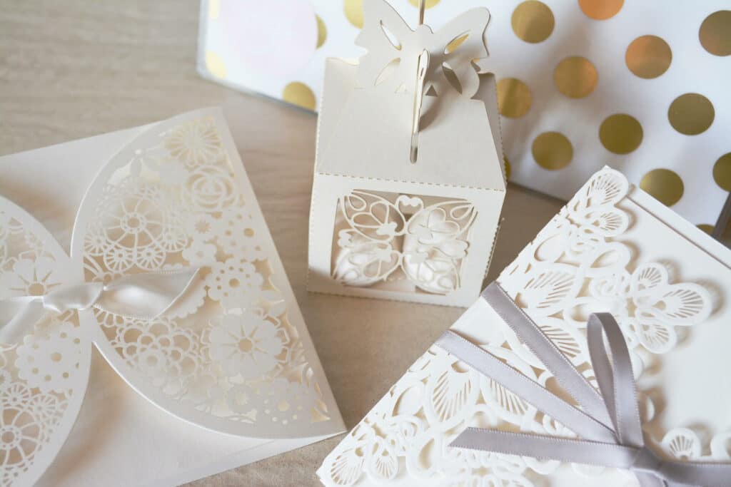 Wedding gifts and cards wrapped in white and gold paper sitting on a table.