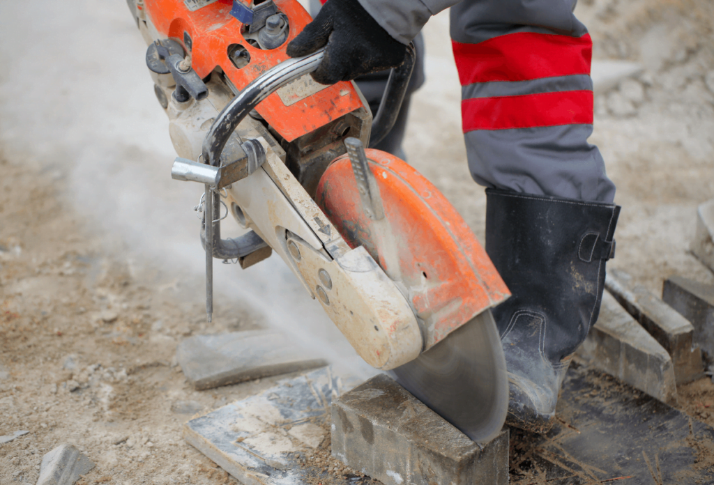A construction worker operating a handheld saw, but can work safely because of construction site security.