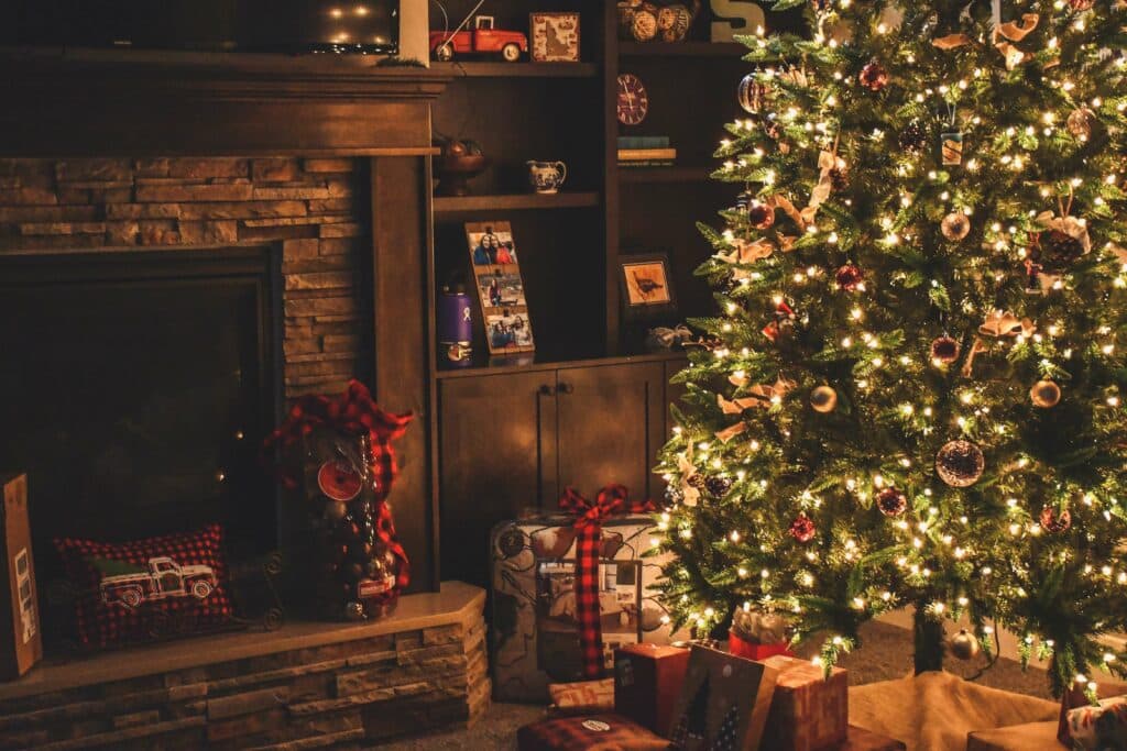 A Christmas tree with lights on and presents underneath. Check your decorations for fire safety.