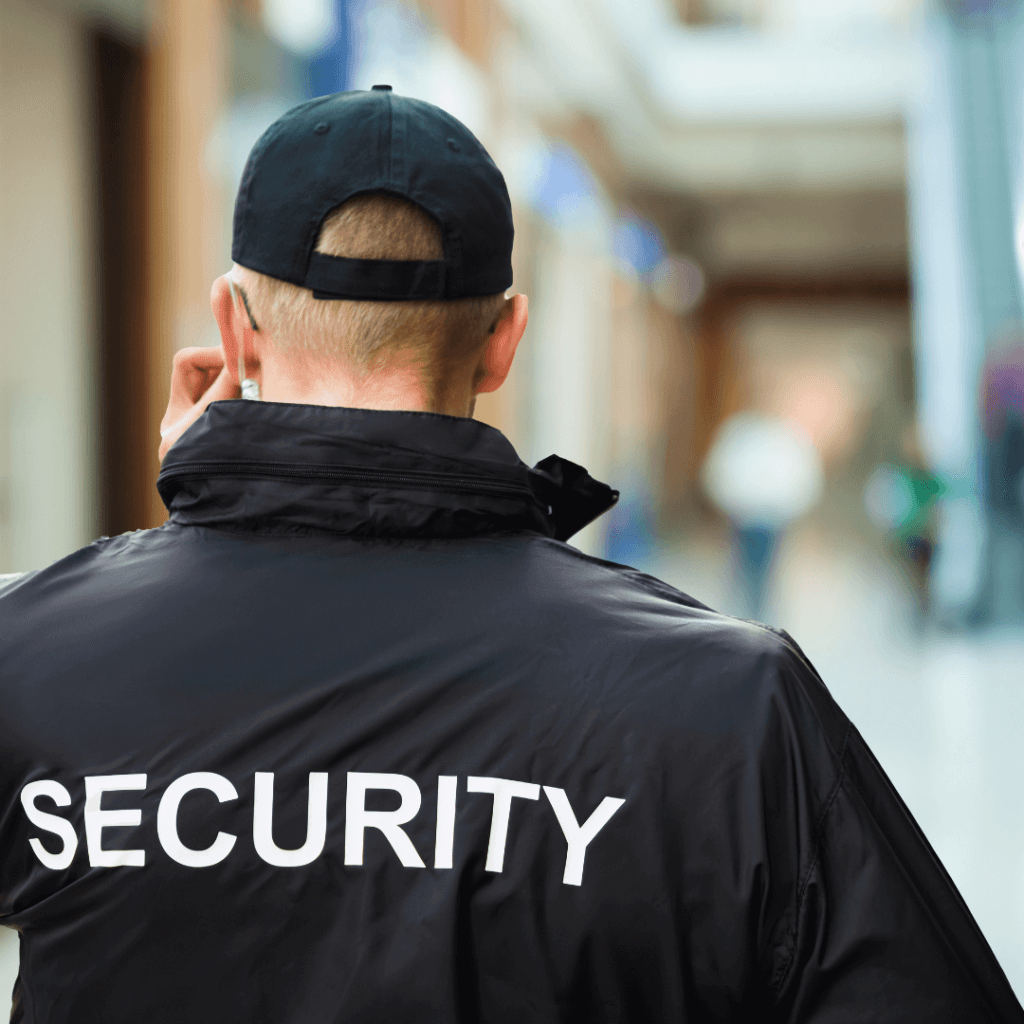The back of a security guard patrolling a business, wearing a jacket that says security