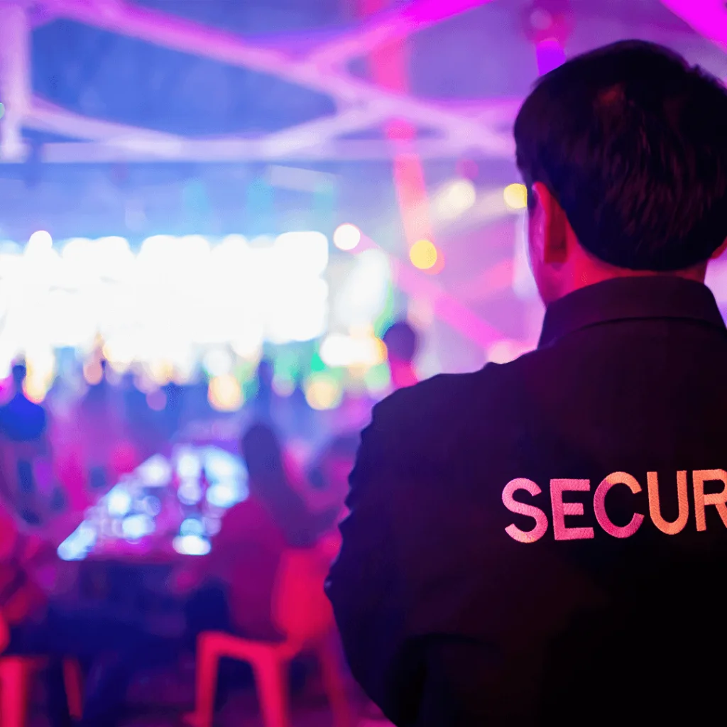 A security guard overlooking a party with pink and blue flashing lights